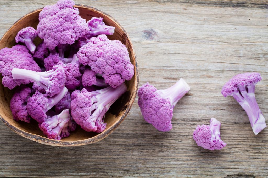 Rainbow of organic cauliflower on the wooden table.