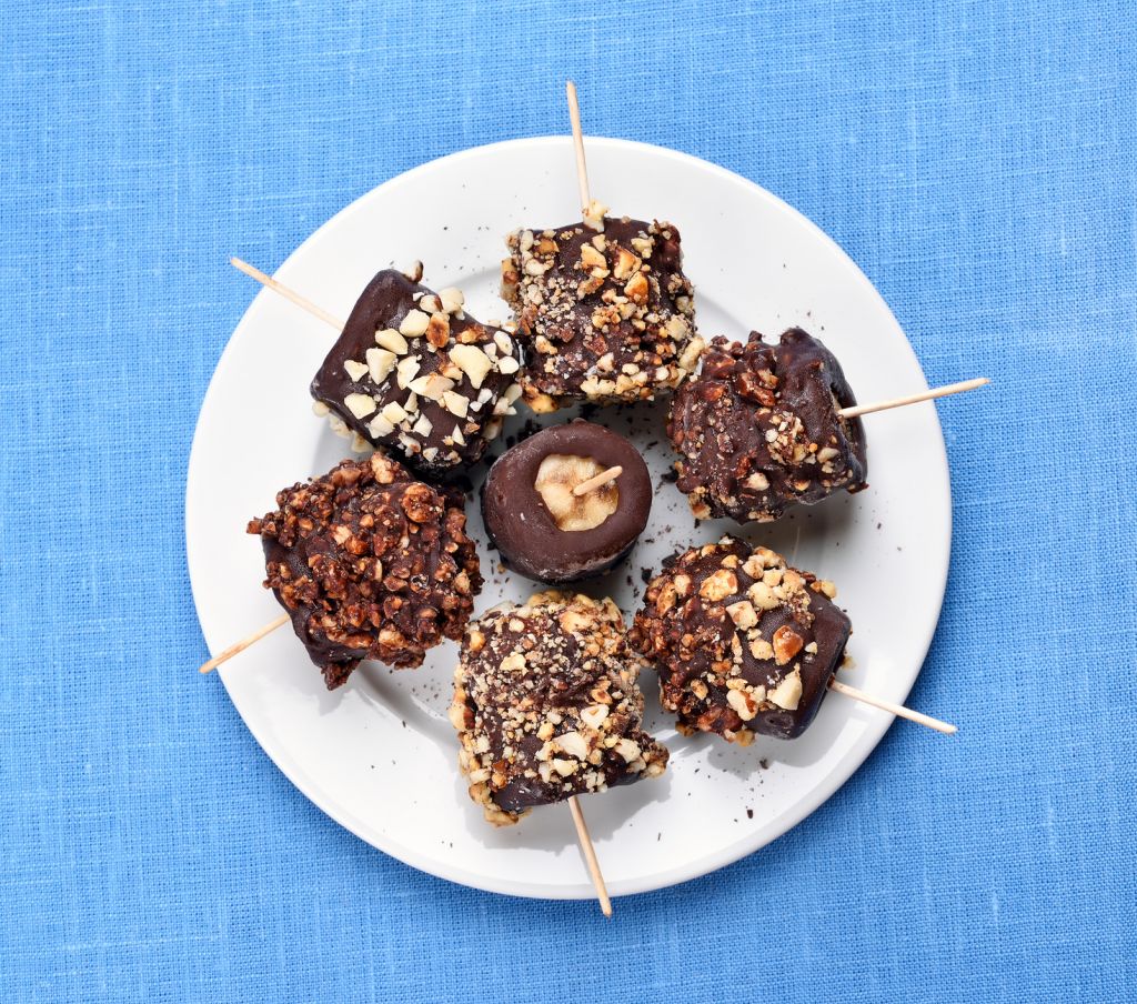 Sweet snack frozen banana covered with chocolate and nuts, top view