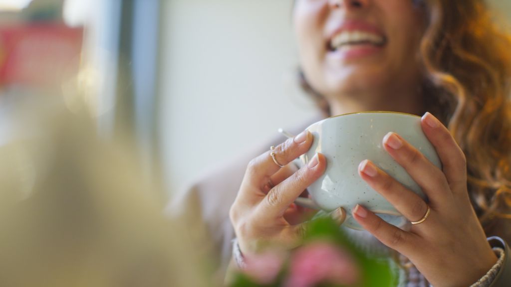 Female hands holding a cup whilst talking happily