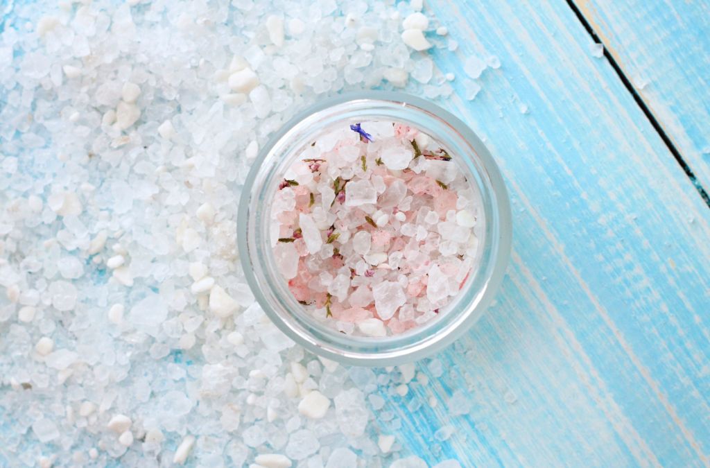 Herbal sea salt scattered, aromatic herbs in jar, on wooden table