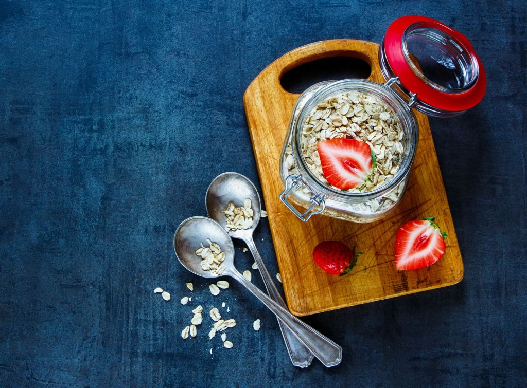 Oat flakes in gar with fresh strawberries for breakfast on dark vintage background with space for text. Healthy food, Diet, Detox, Clean Eating or Vegetarian concept.