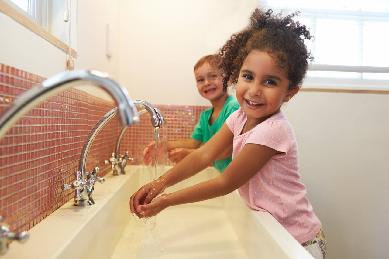Children washing hands in a bathroom in a child care facility in Contra Costa County representing healthy practices at a child care facility.