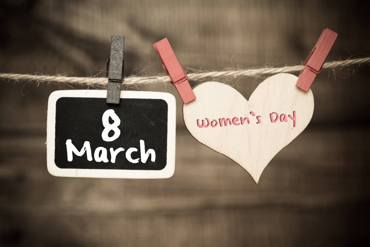 A wooden heart and chalkboard reading March 8th International Women's Day hanging on a twine line, celebrating women in child care.