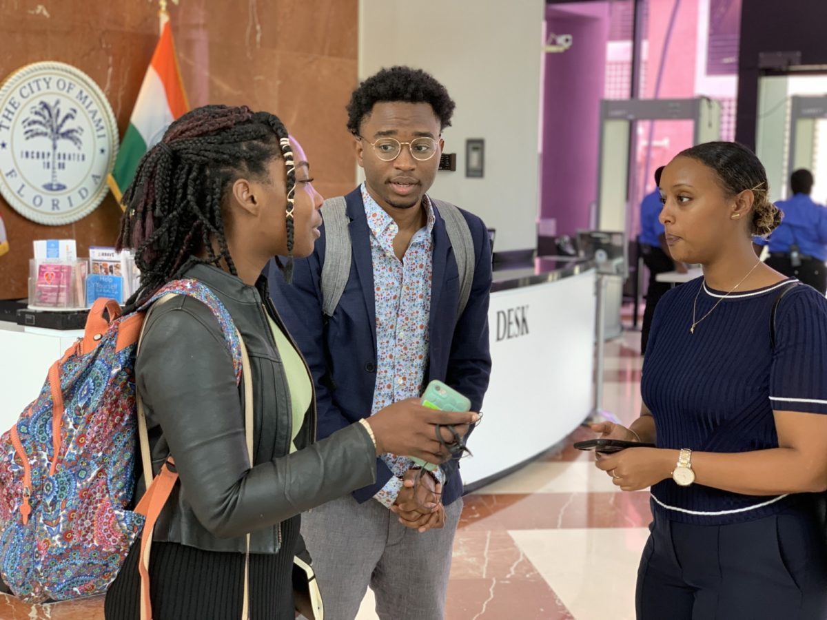 Group of three chatting in front of City of Miami seal