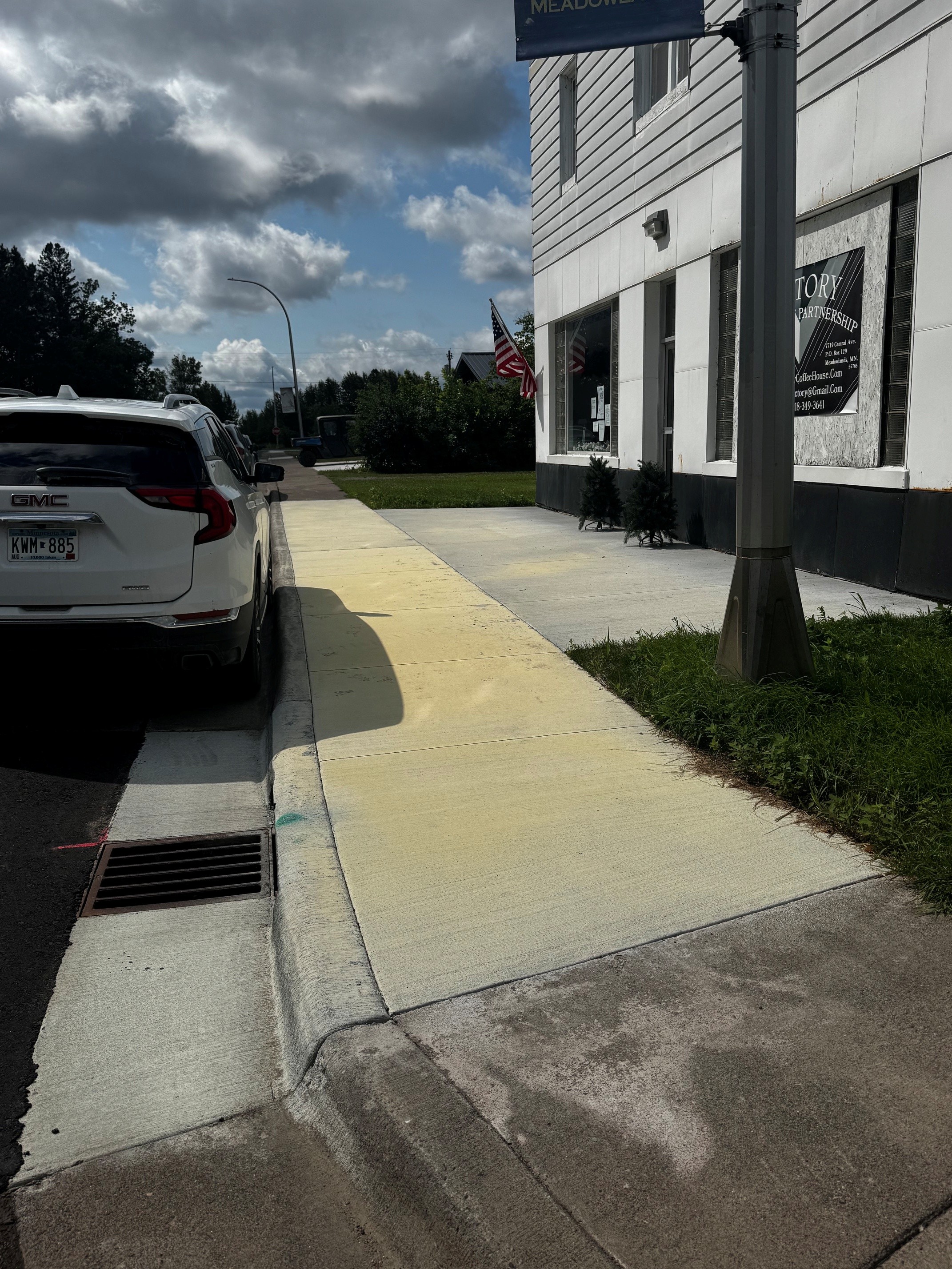 New sidewalk in front of building and car parked by it