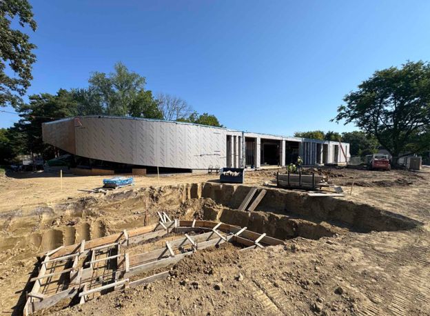 Image shows newly under construction framing and walls of Westonka Library in background and concrete forms in dirt in the foreground.