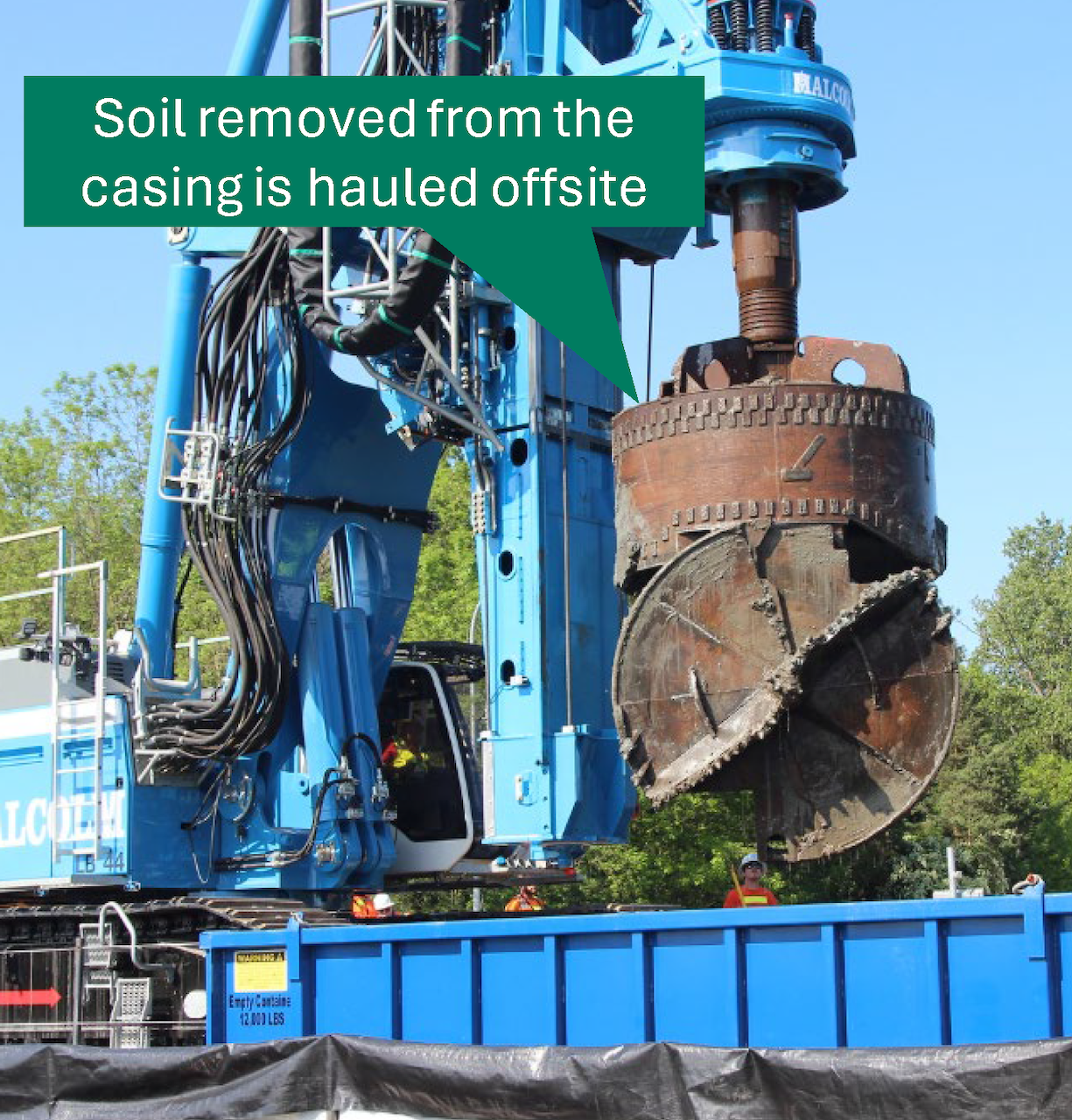 A cylindrical drill dumping soil into a container.