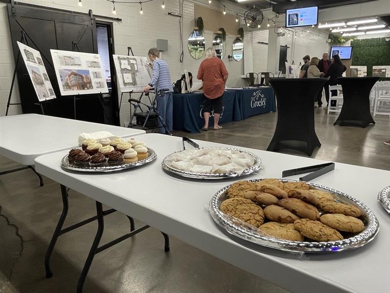 Snacks line a table while attendees look at project poster boards.