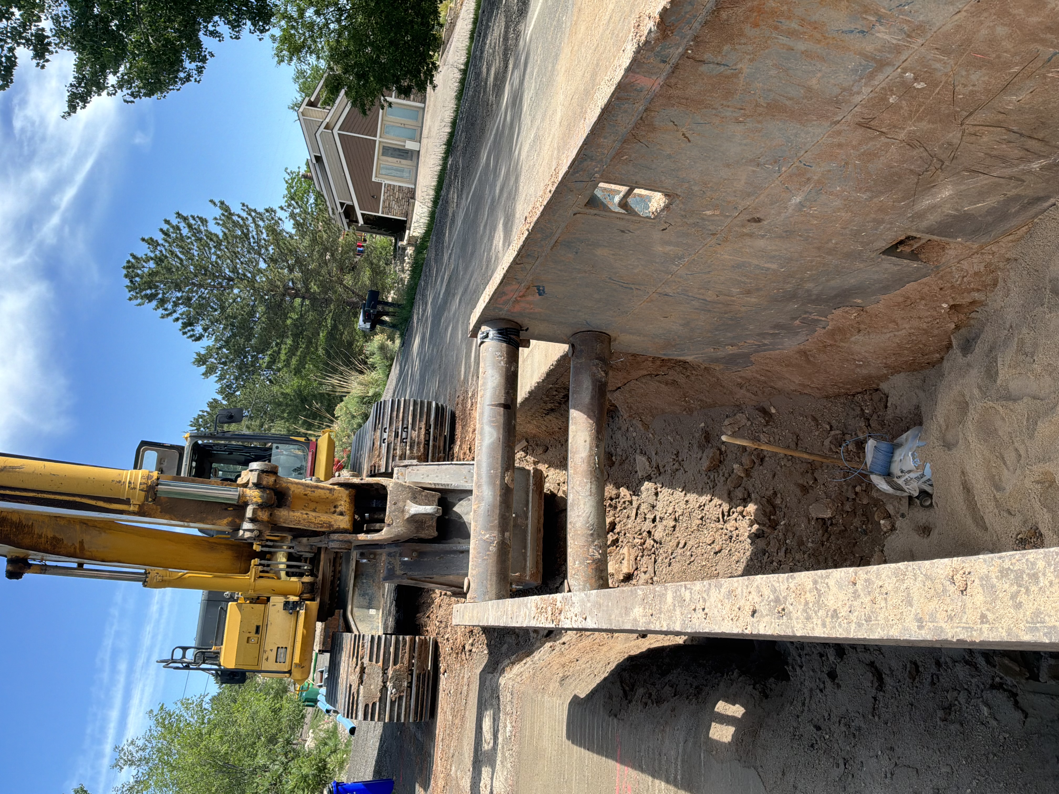 Construction trench with heavy digging equipment shown behind.