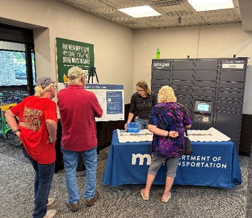 A photo of MnDOT staff talking with members of the public at Brinks Market.