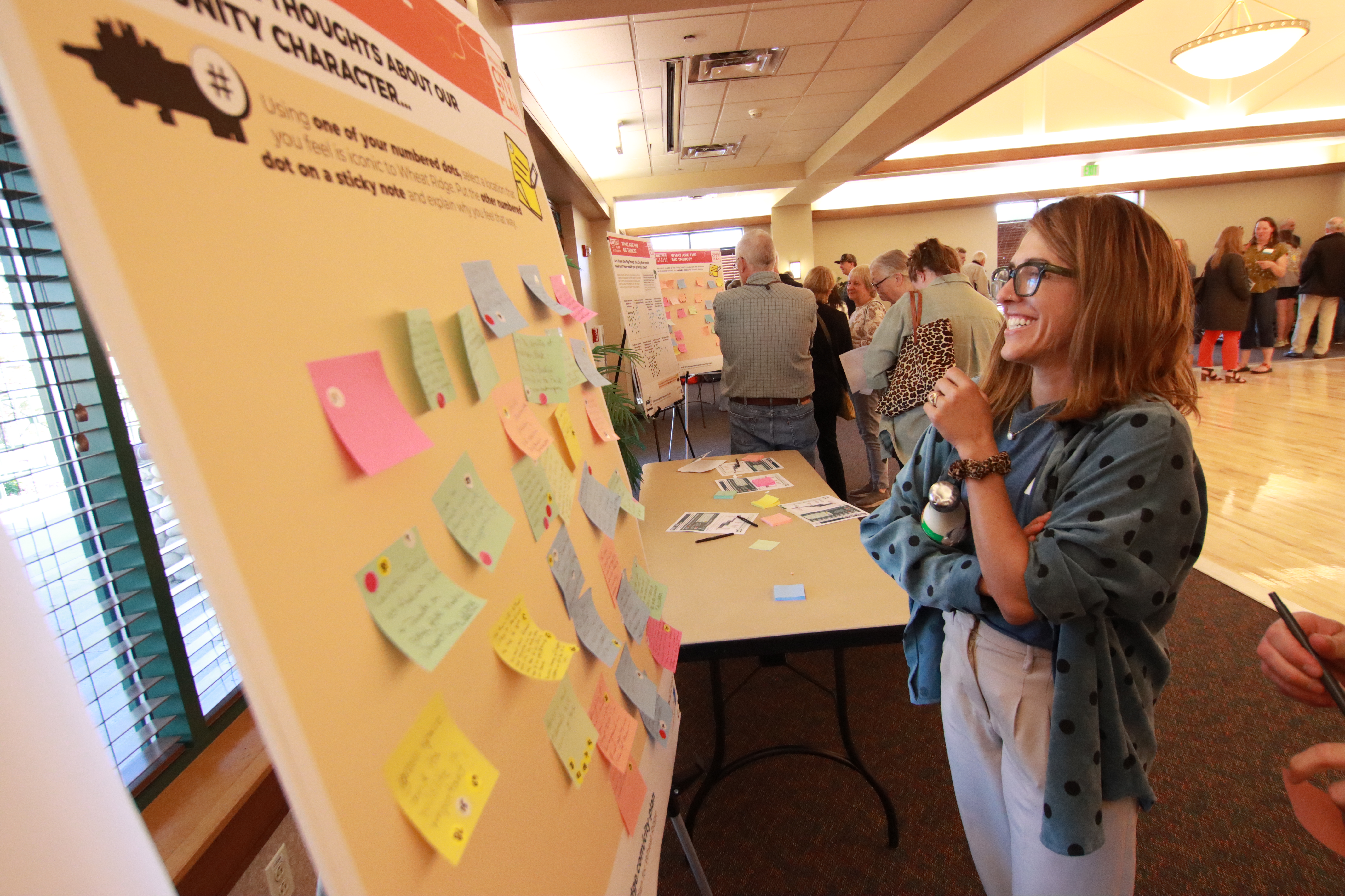 Woman grins at comment board at public open house.