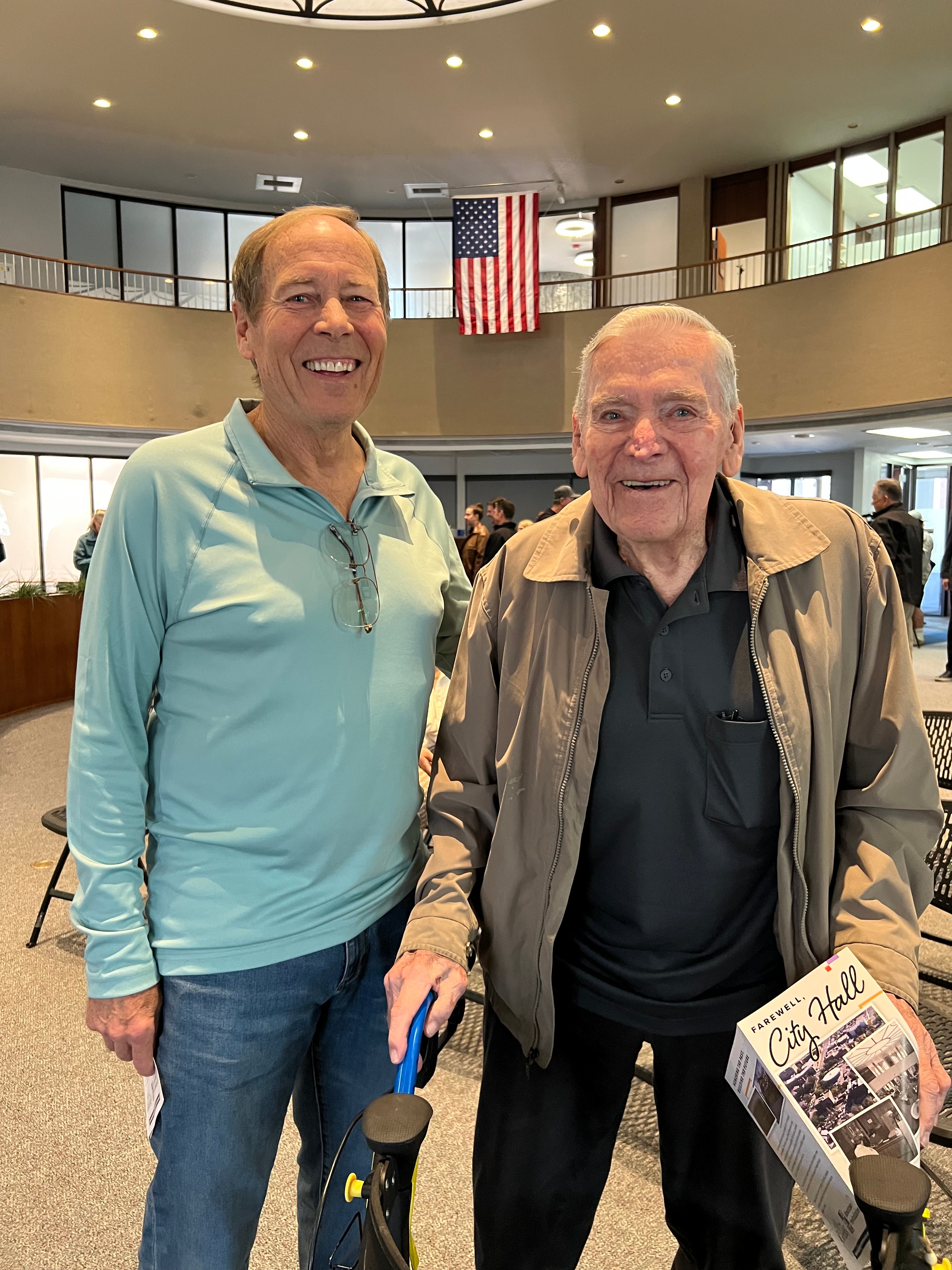 Two attendees smiling, holding the event program.