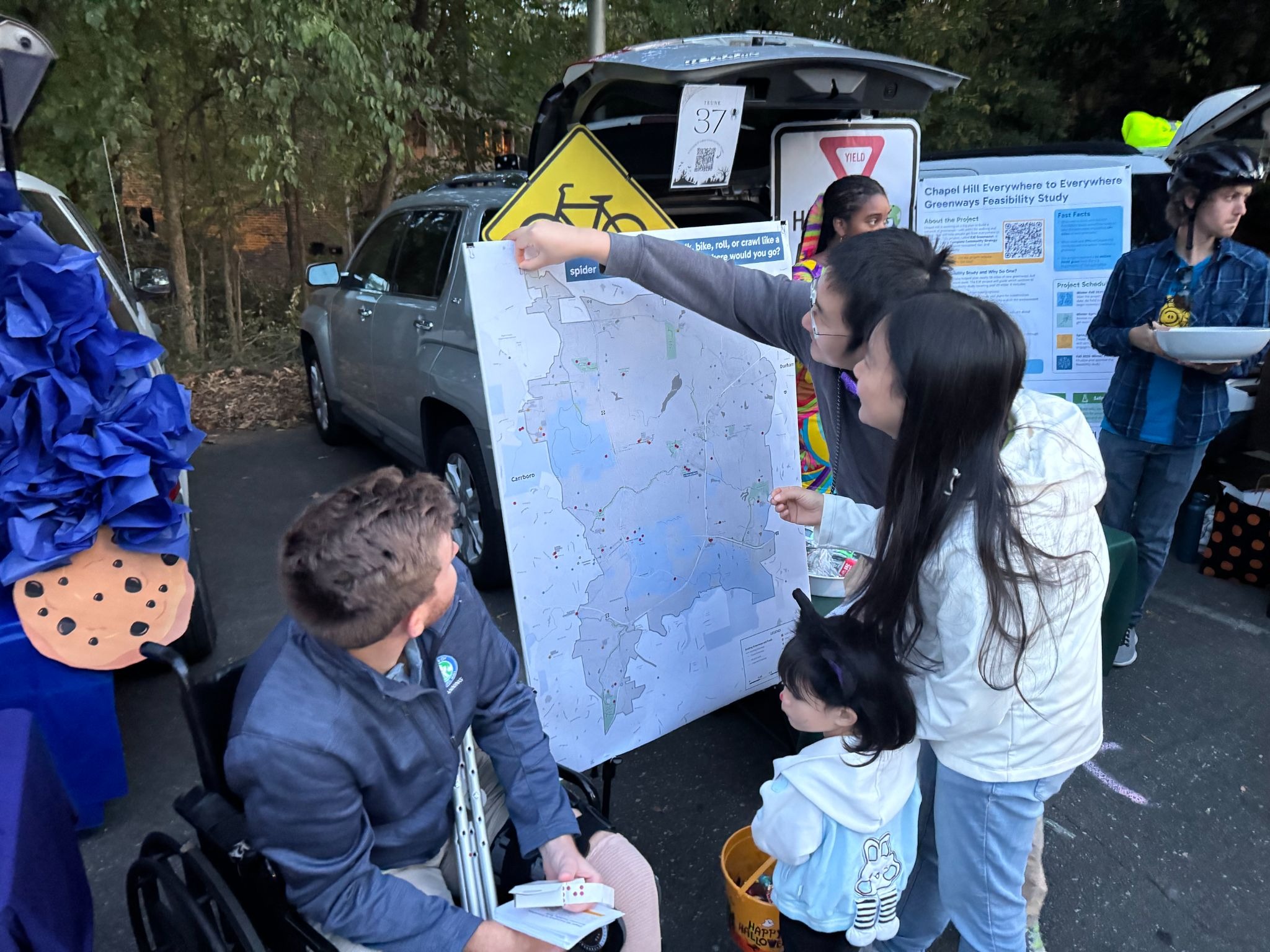 People at Haunted Hill Trunk or Treat look a map of greenways in Chapel Hill