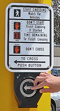Hand pressing ADA accessible walk signal button