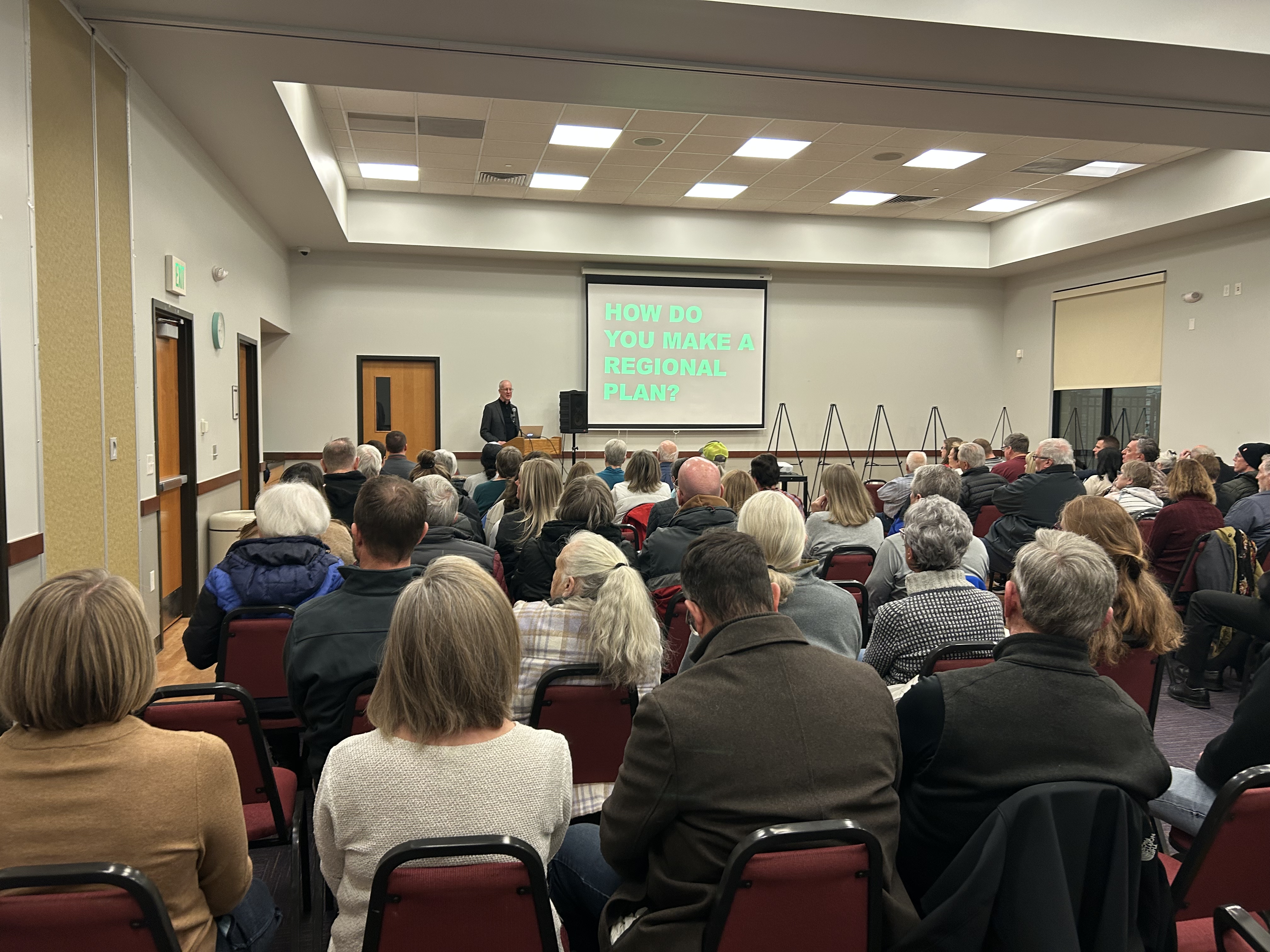 Community members fill a meeting room while Jeff Speck explains planning concepts during the Westside Area Plan open house.