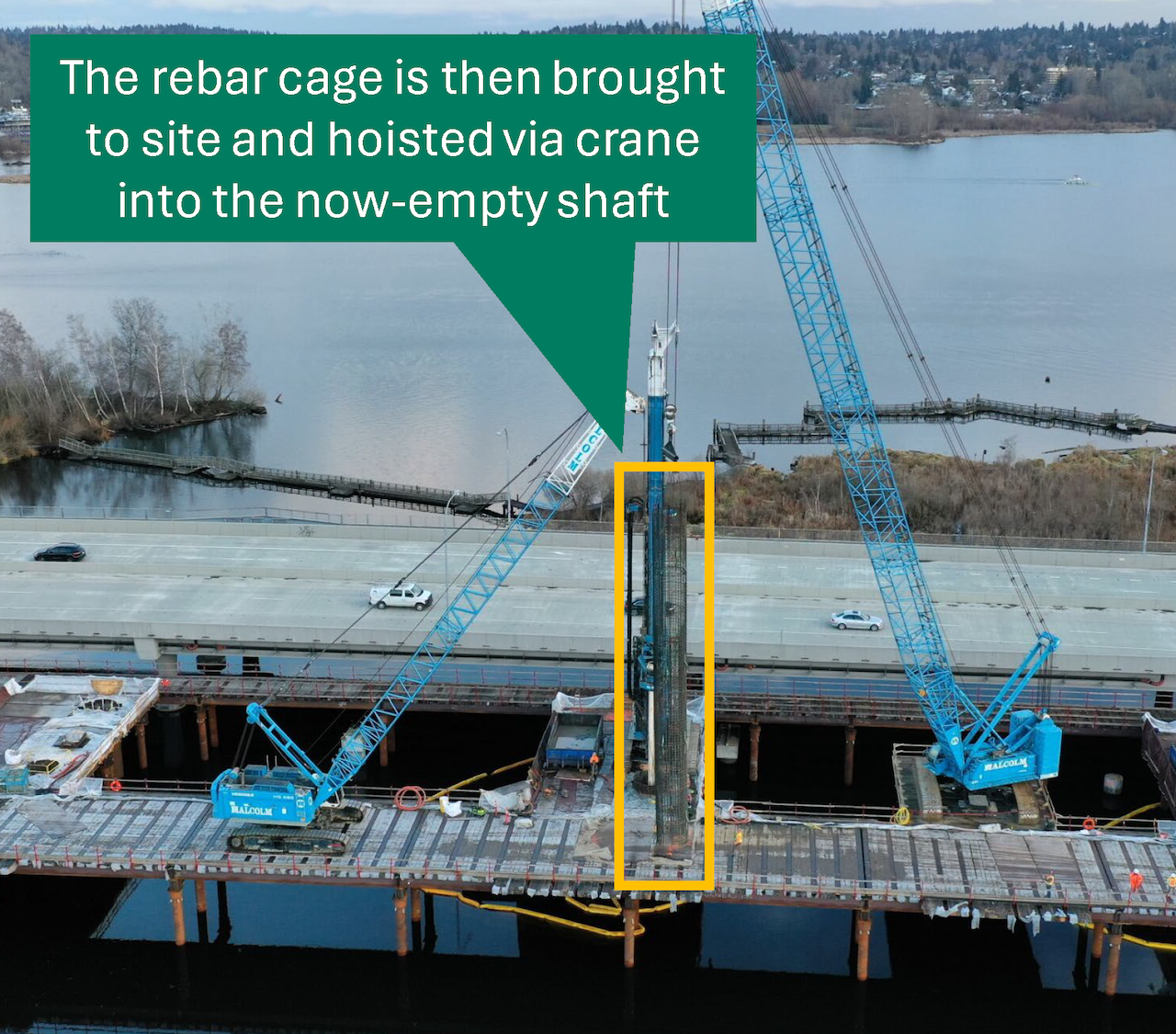 Two cranes on a work trestle lower a rebar cage into an empty casing. 