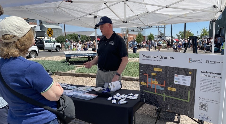 a person talks with another at a project information booth.