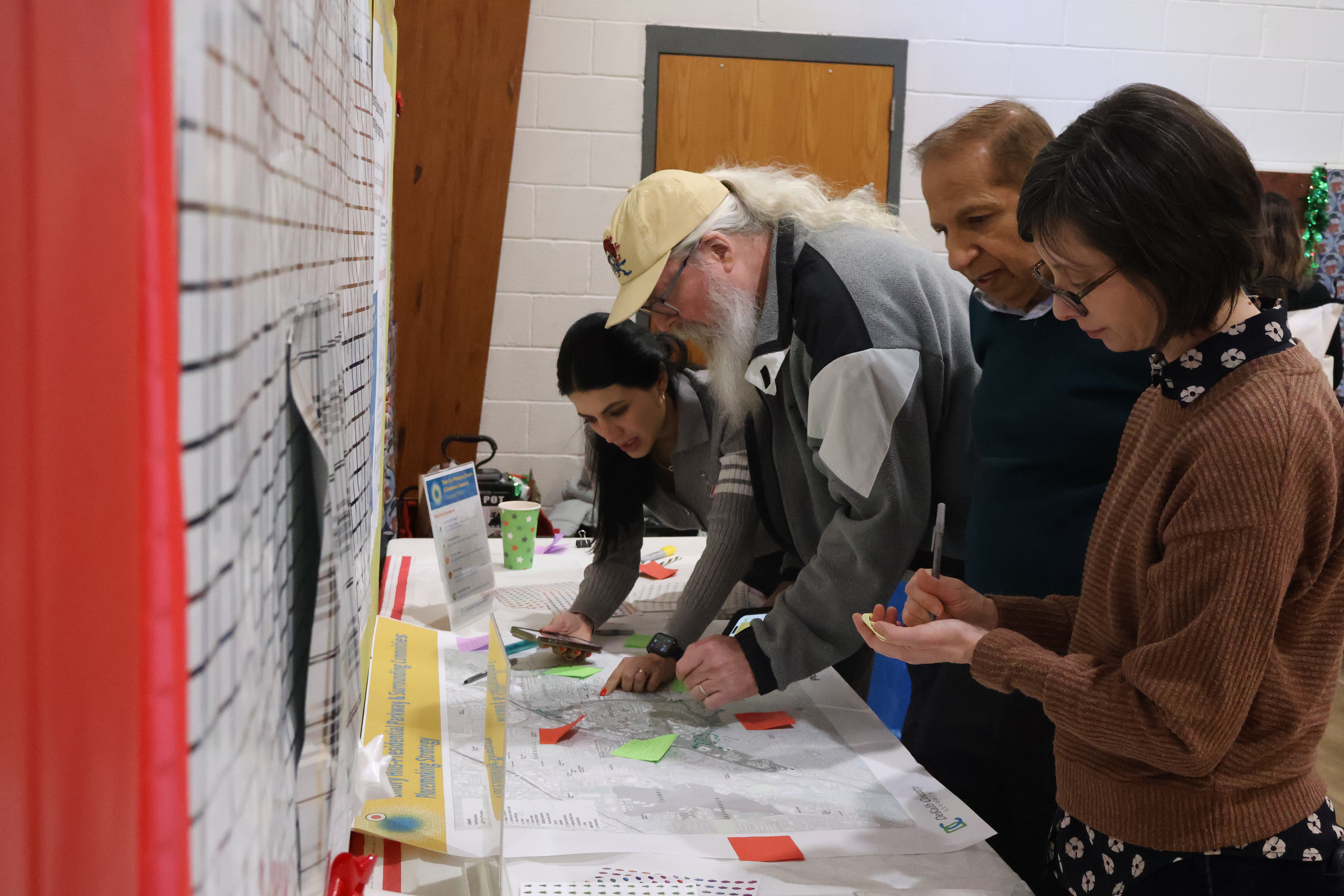 Group of people at a community meeting looking over information on a table.