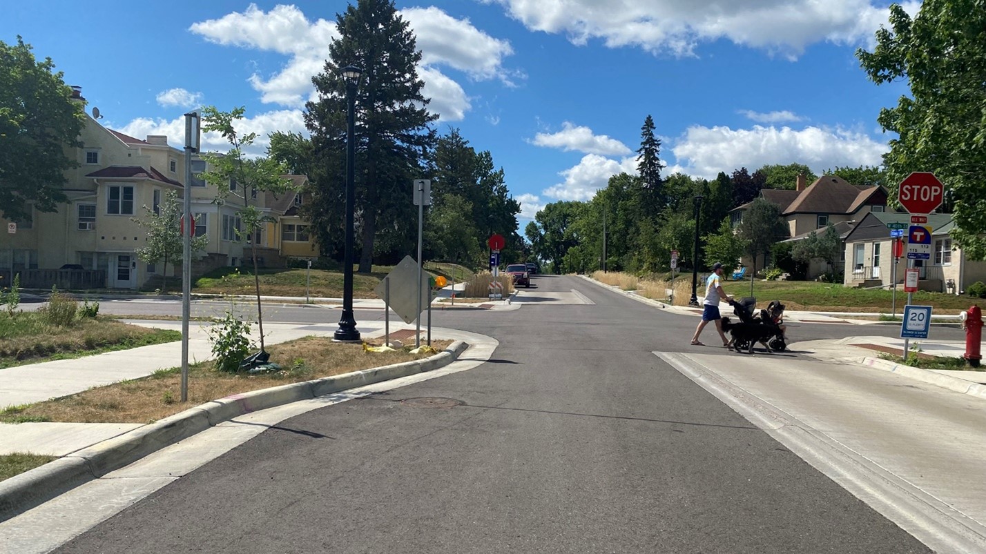 A person walking across the street pushing a stroller