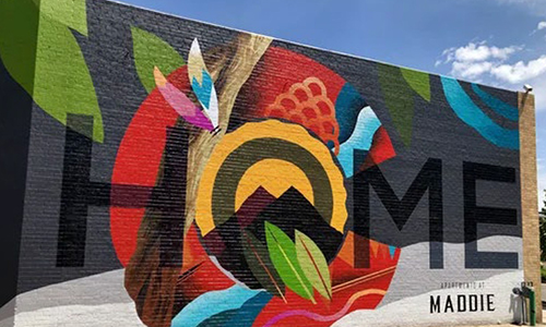 A large, outdoor mural reads, "home"