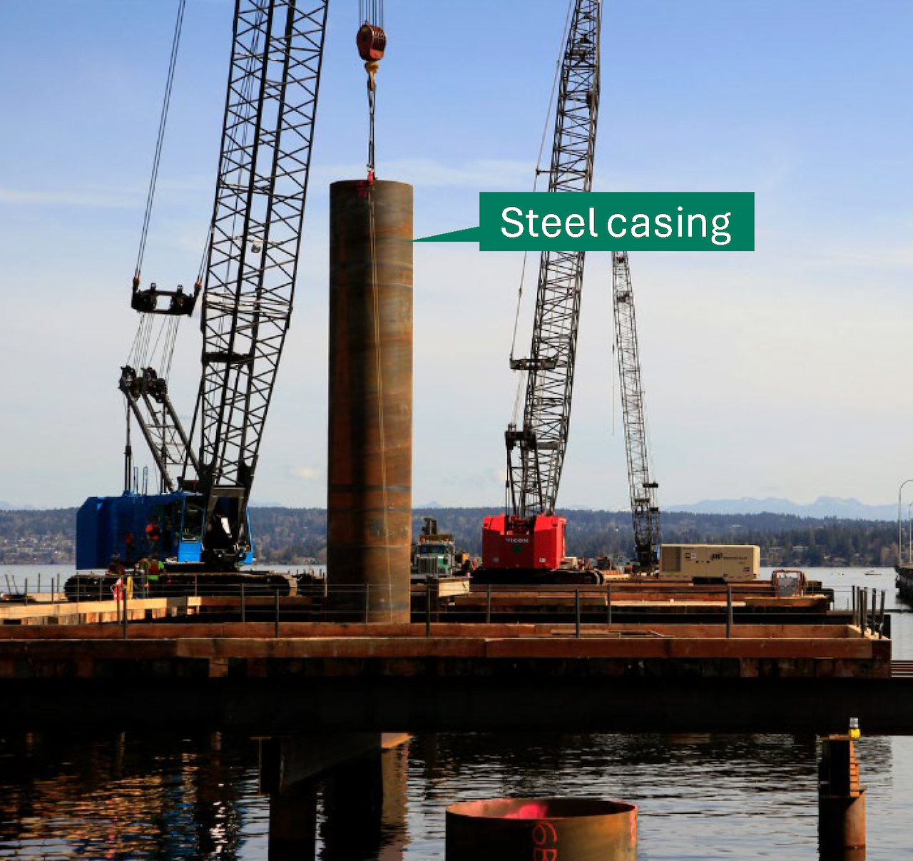 A steel casing lowered into water by a crane.