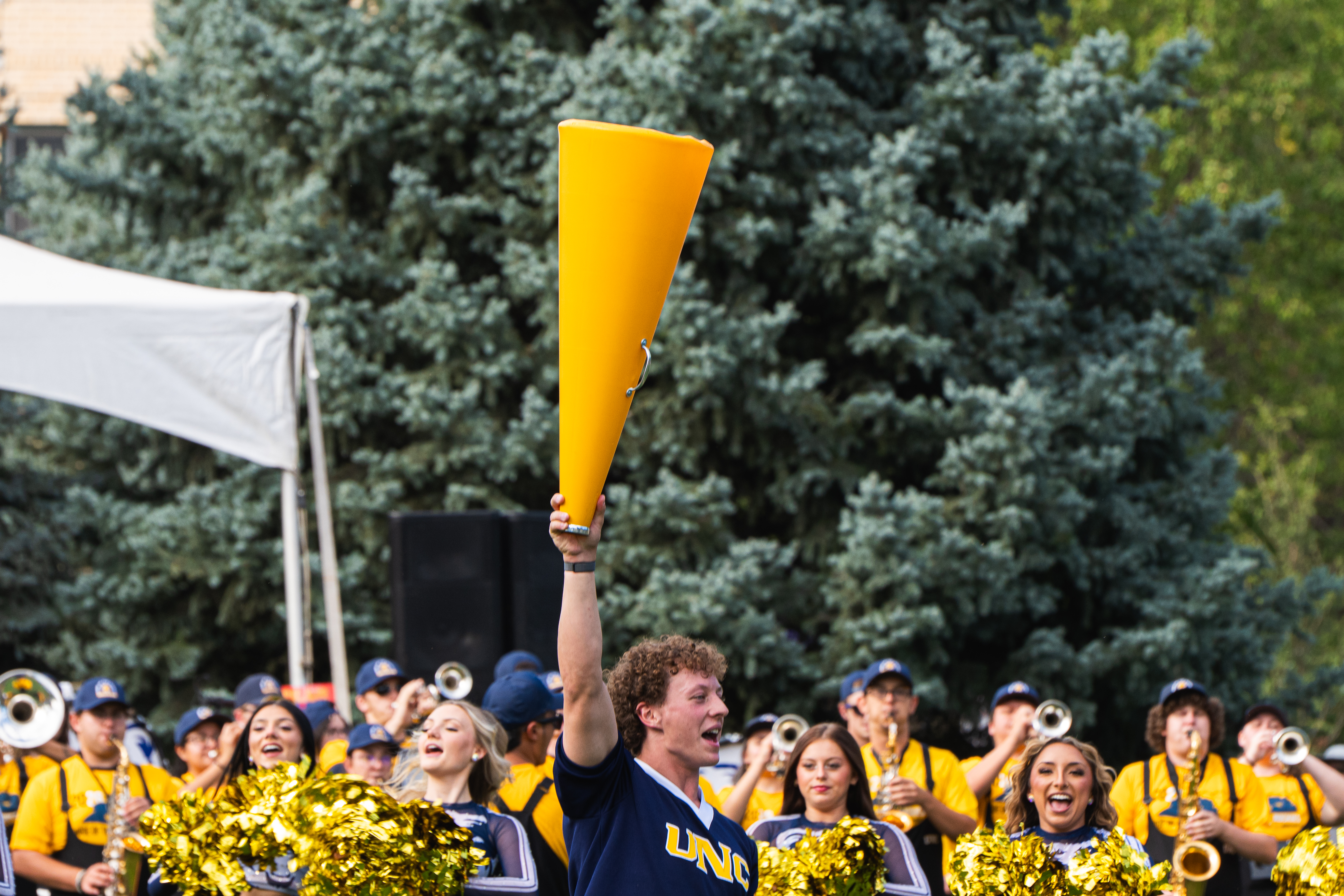 A UNC student holds a megaphone in the air as the UNC marching band and cheerleaders perform during Bear Bash.