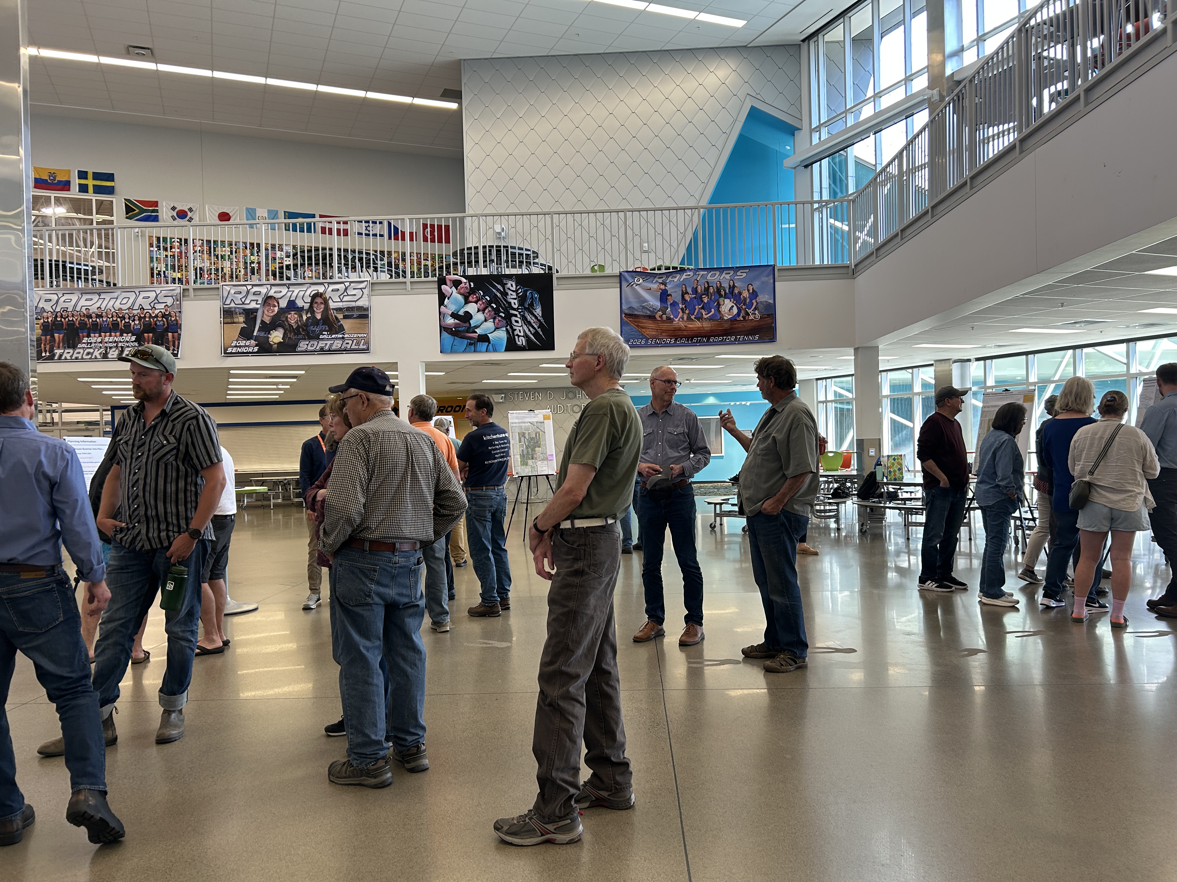 A group of people stand viewing display boards at an open house.