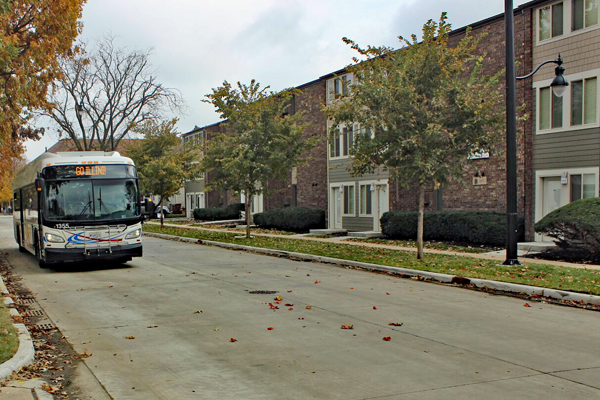 Row of 3-story apartment buildings facing a residential street with an MTD bus.
