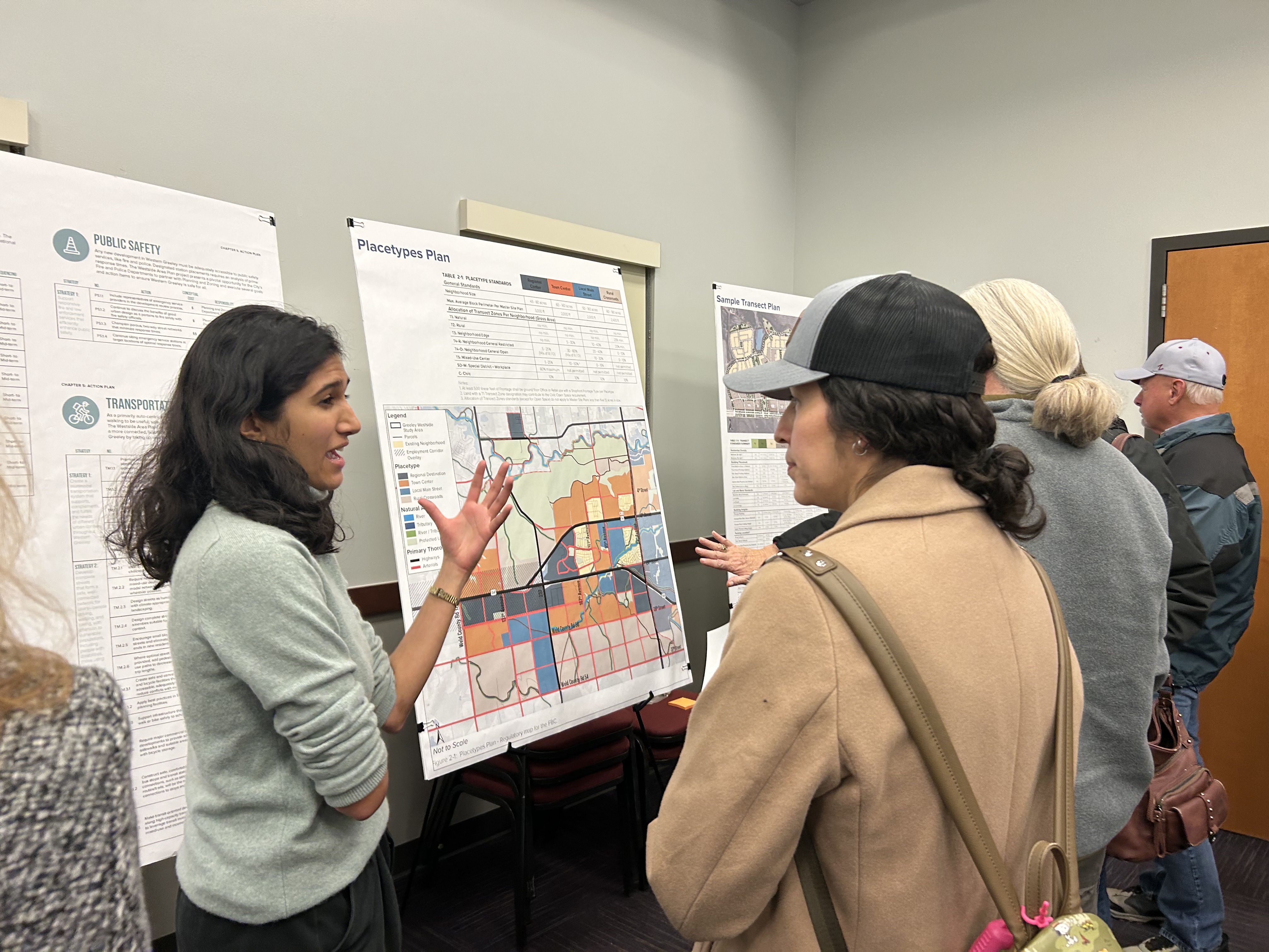 Community members stand around display boards while a presenter explains a map and planning concepts during a Westside Area Plan open house.