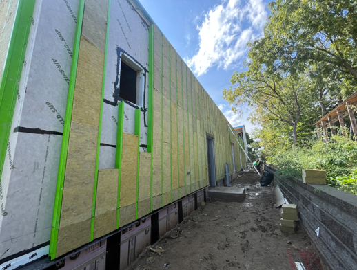 This image shows the exterior of the building being prepped for siding with materials being applied.