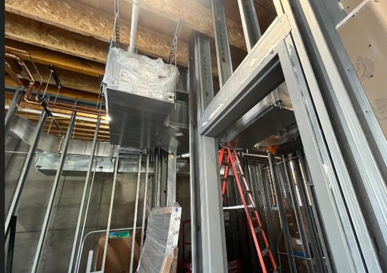 This image shows metal framing with wood beams housing mechanical, electrical, and plumbing pipes.
