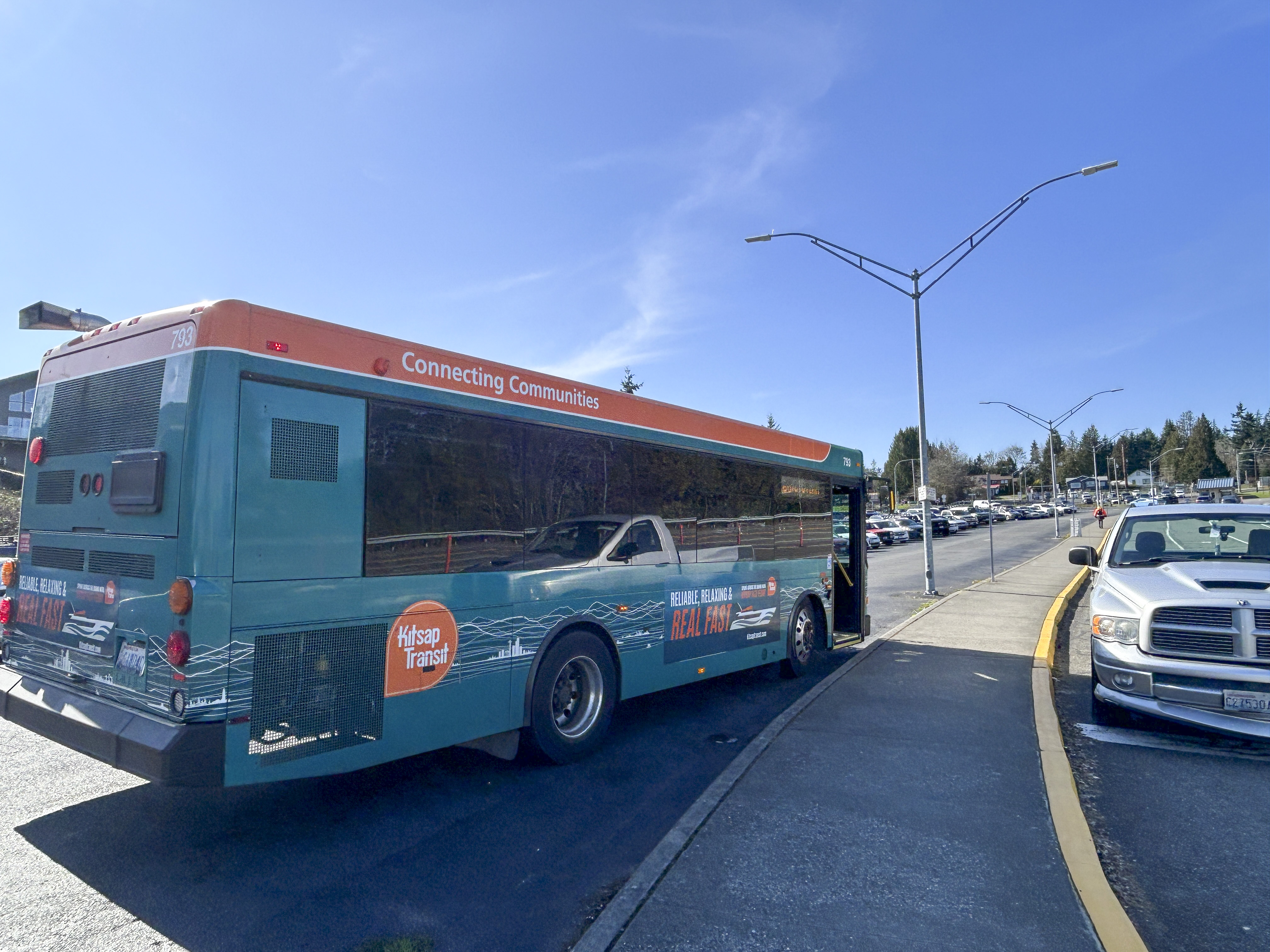 A Kitsap Transit bus stopped at the transit zone next to the parking lot.