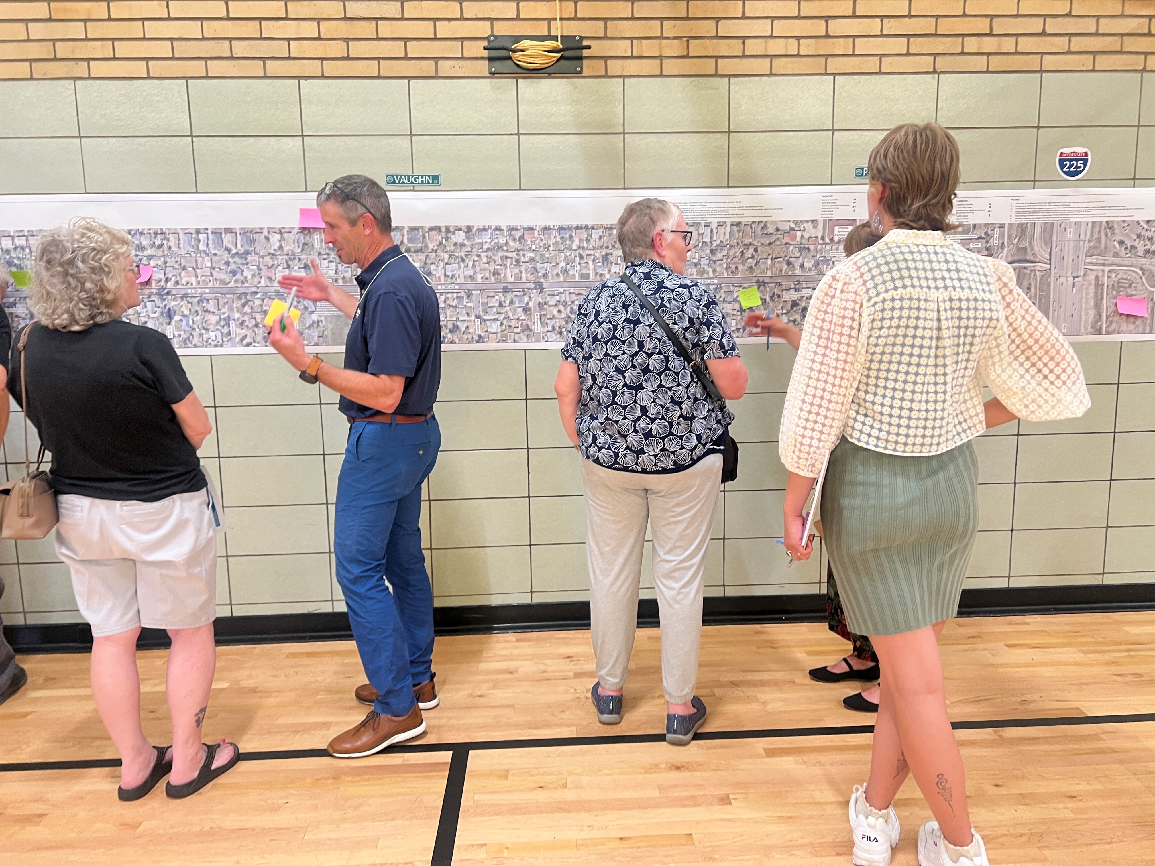 Four people stand by a wall with a horizontal map