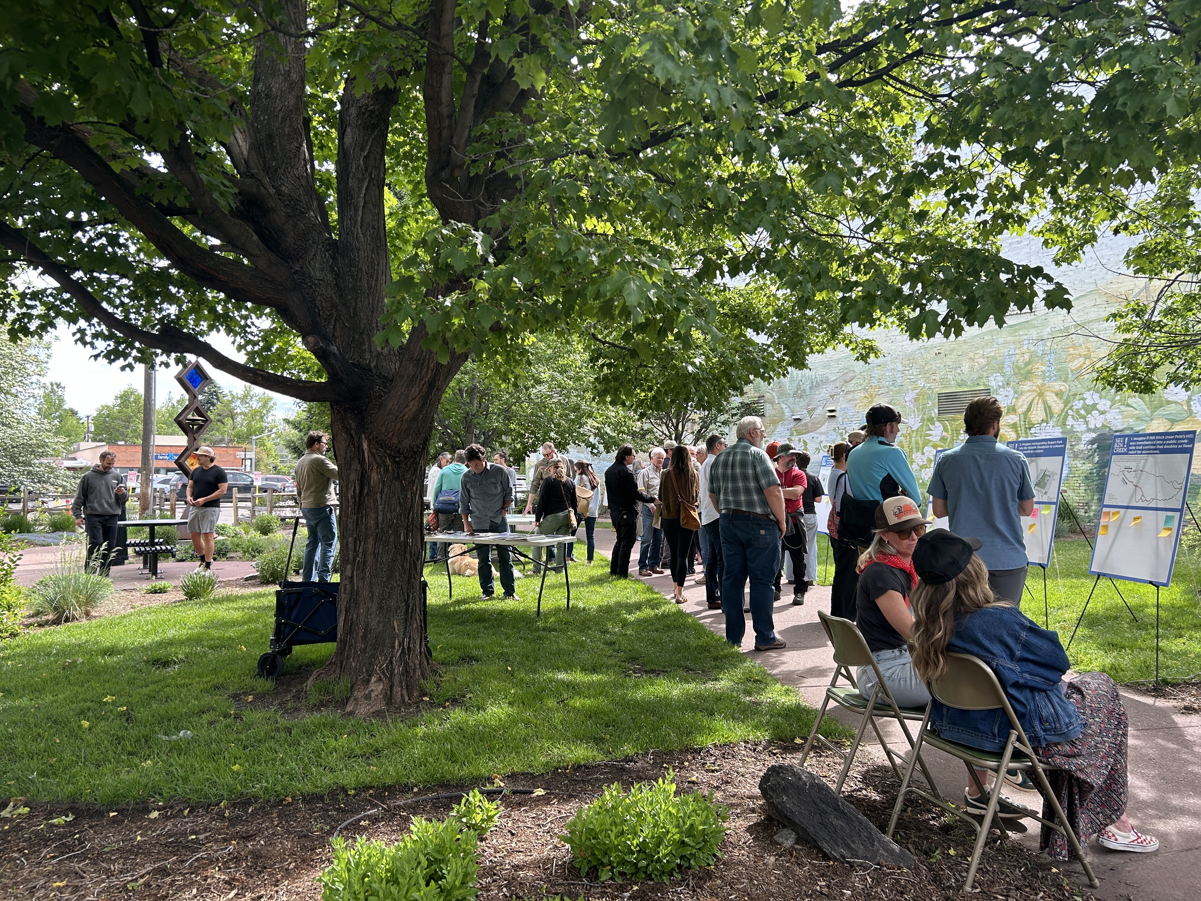 People gather outside at the open house, viewing display boards and talking with each other.