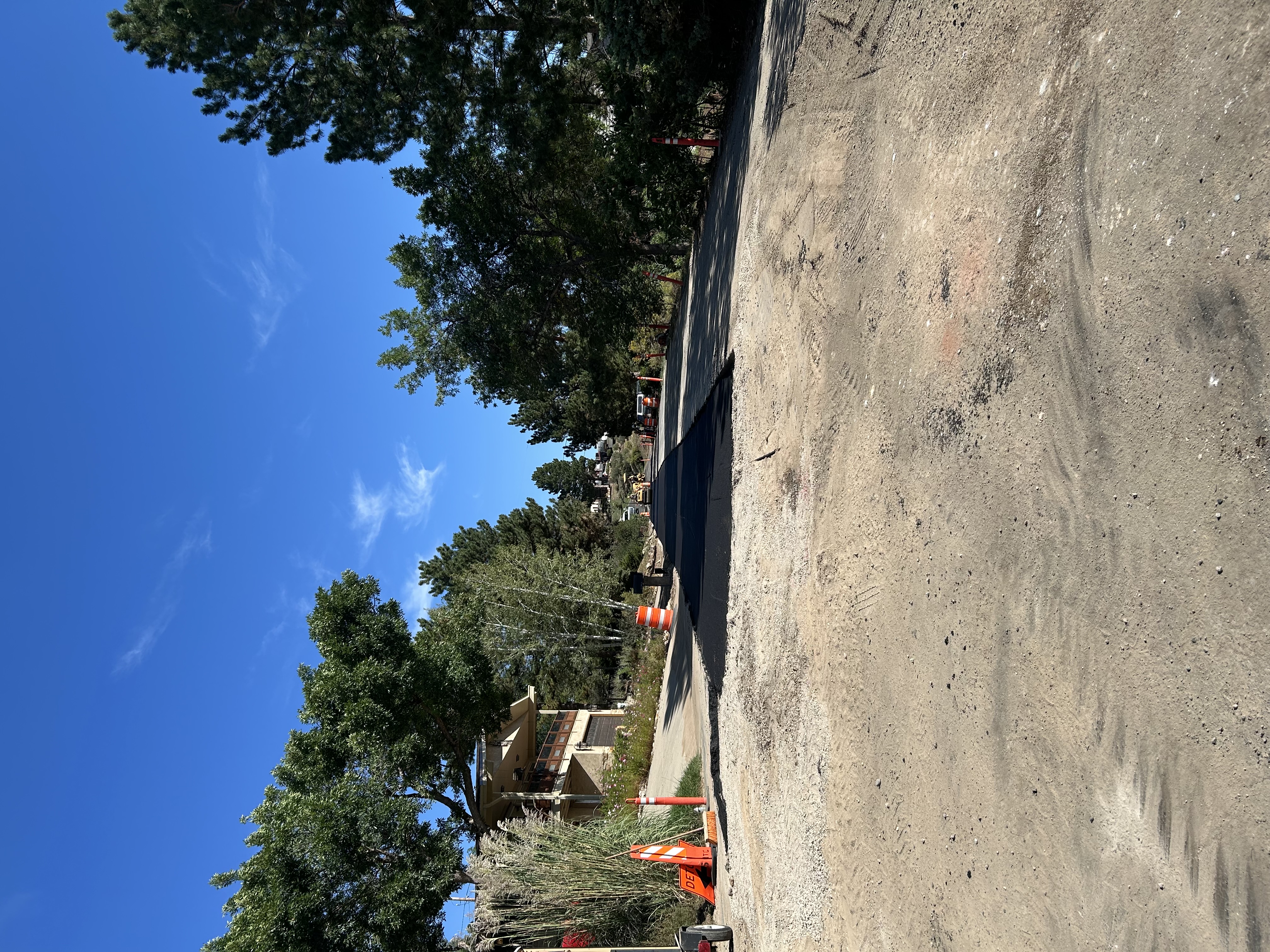 Looking down a street with the left half showing fresh black pavement.