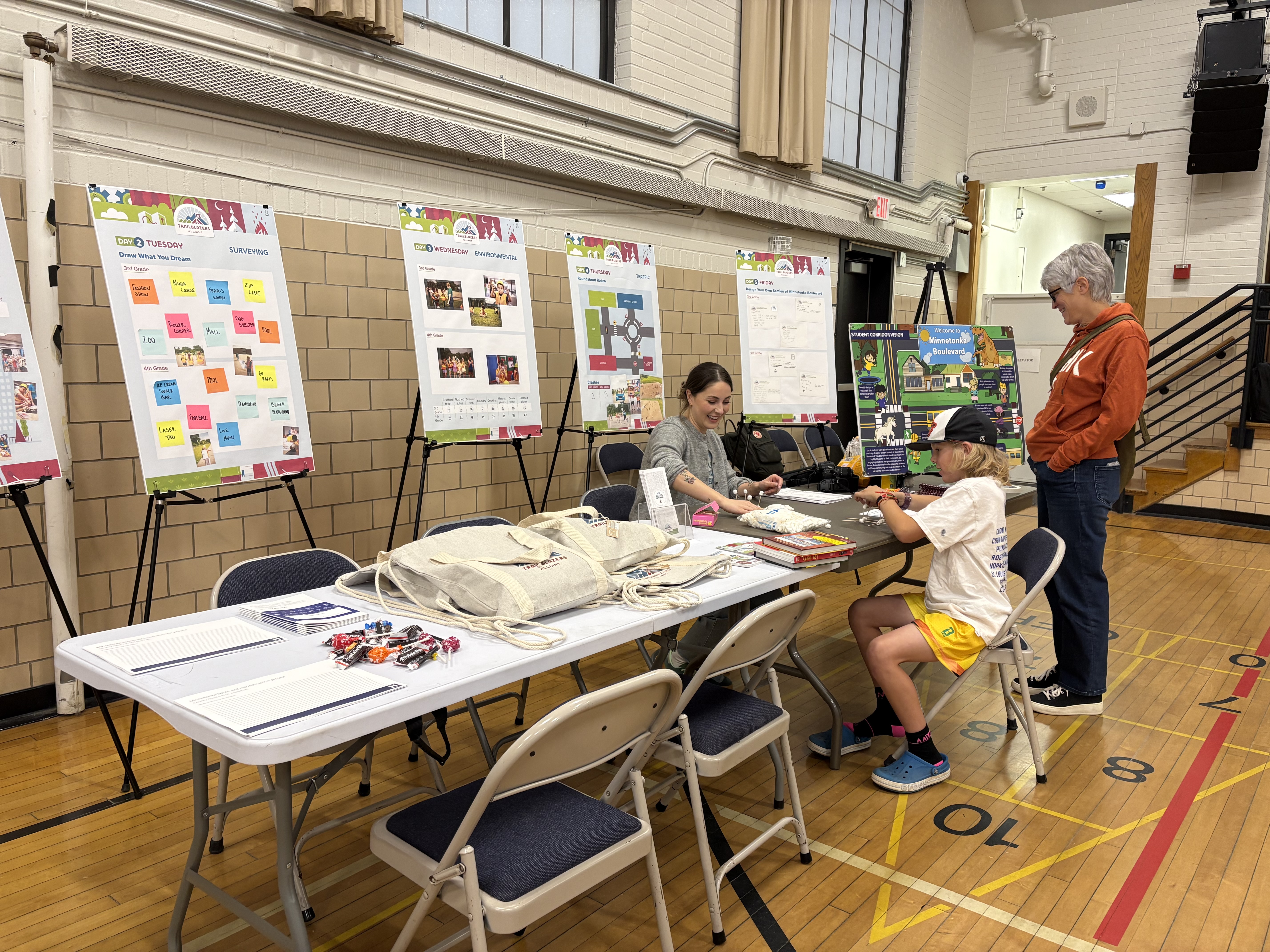 People are sitting at a table doing an activity. There are boards behind the table.