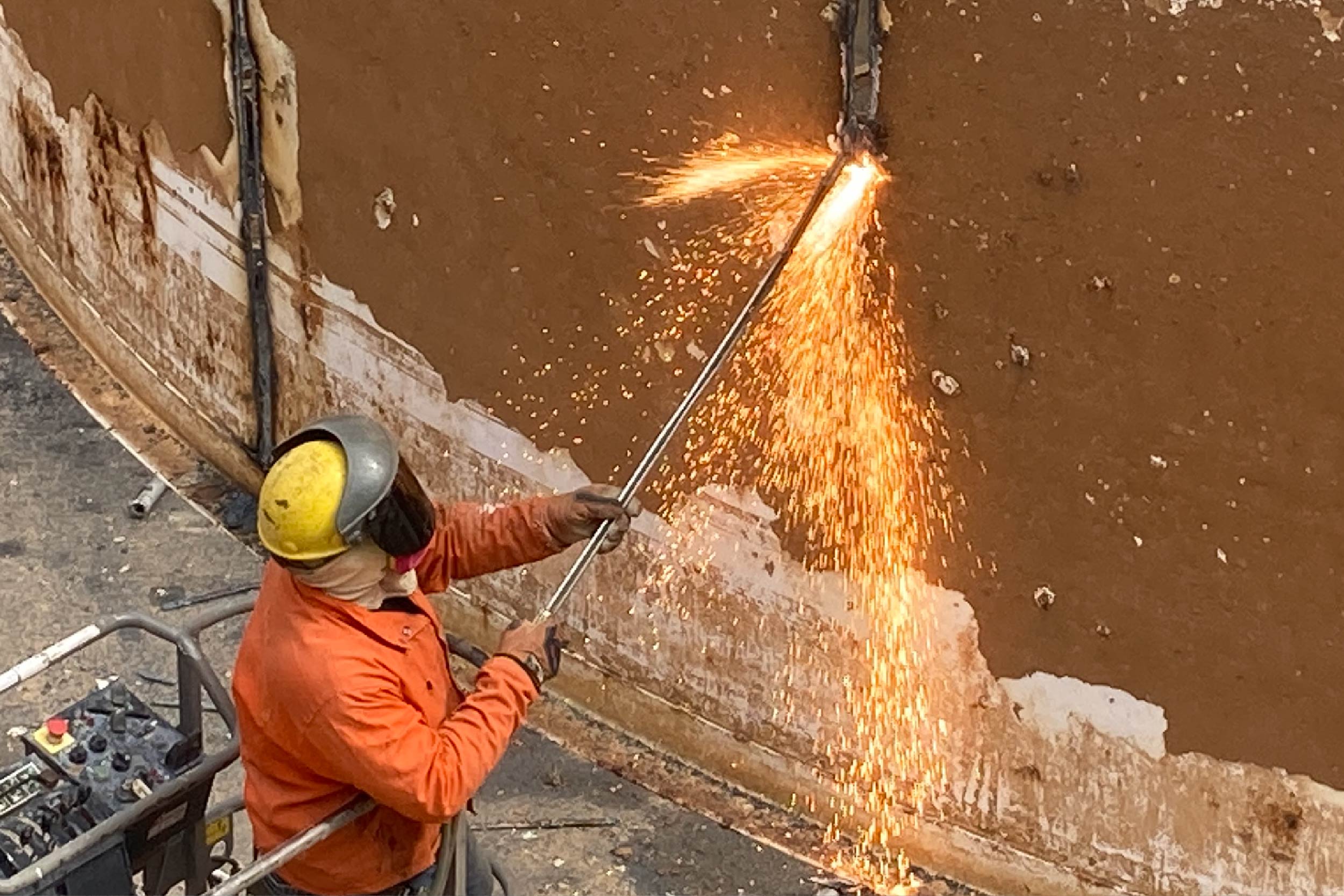 A crew member uses a blow torch to cut pieces of equipment from the clarifier in secondary basin 2.
