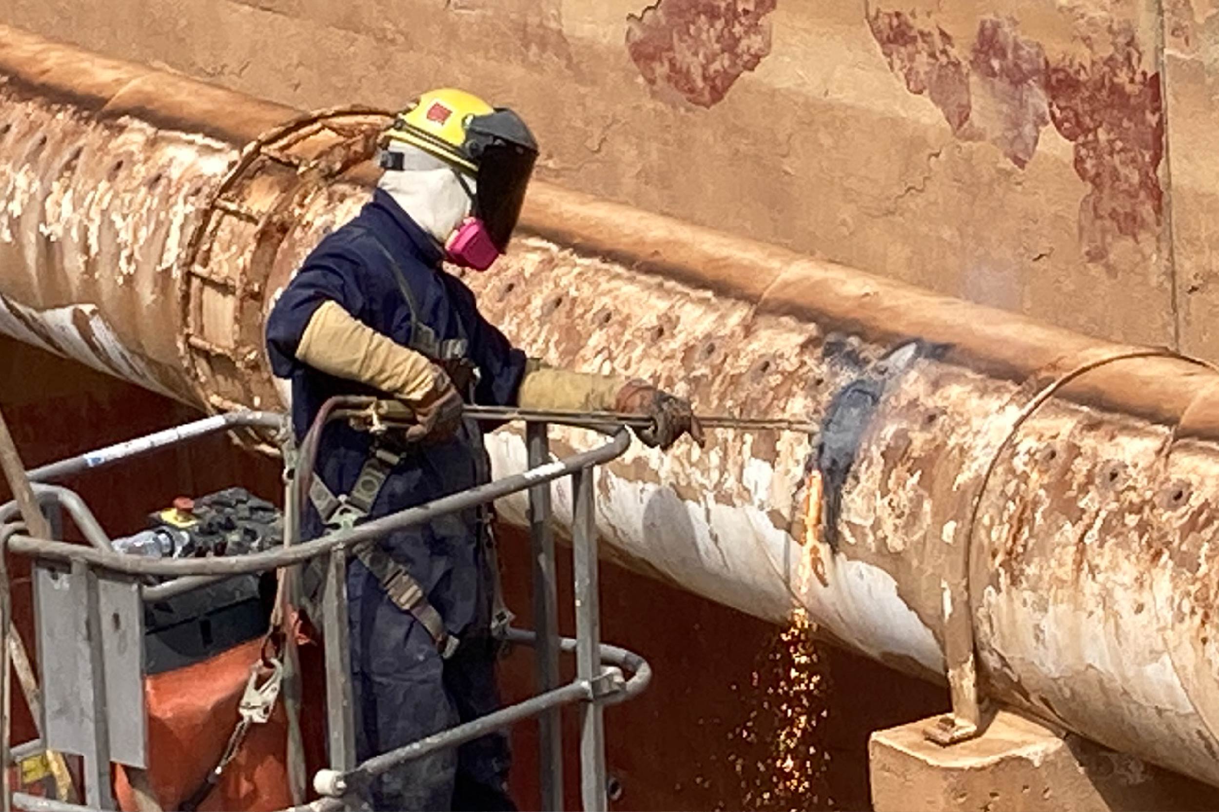 A crew member uses a blow torch to cut pieces of a large water pipe in secondary basin 2