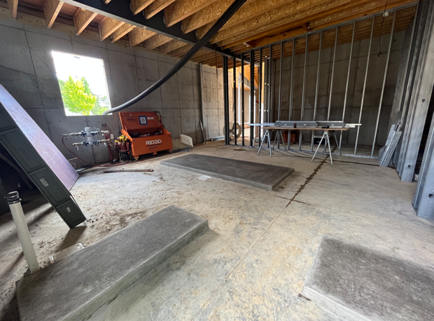 This image shows the mechanical room with concrete walls and floors and concrete rectangular slabs to hold mechanical equipment.