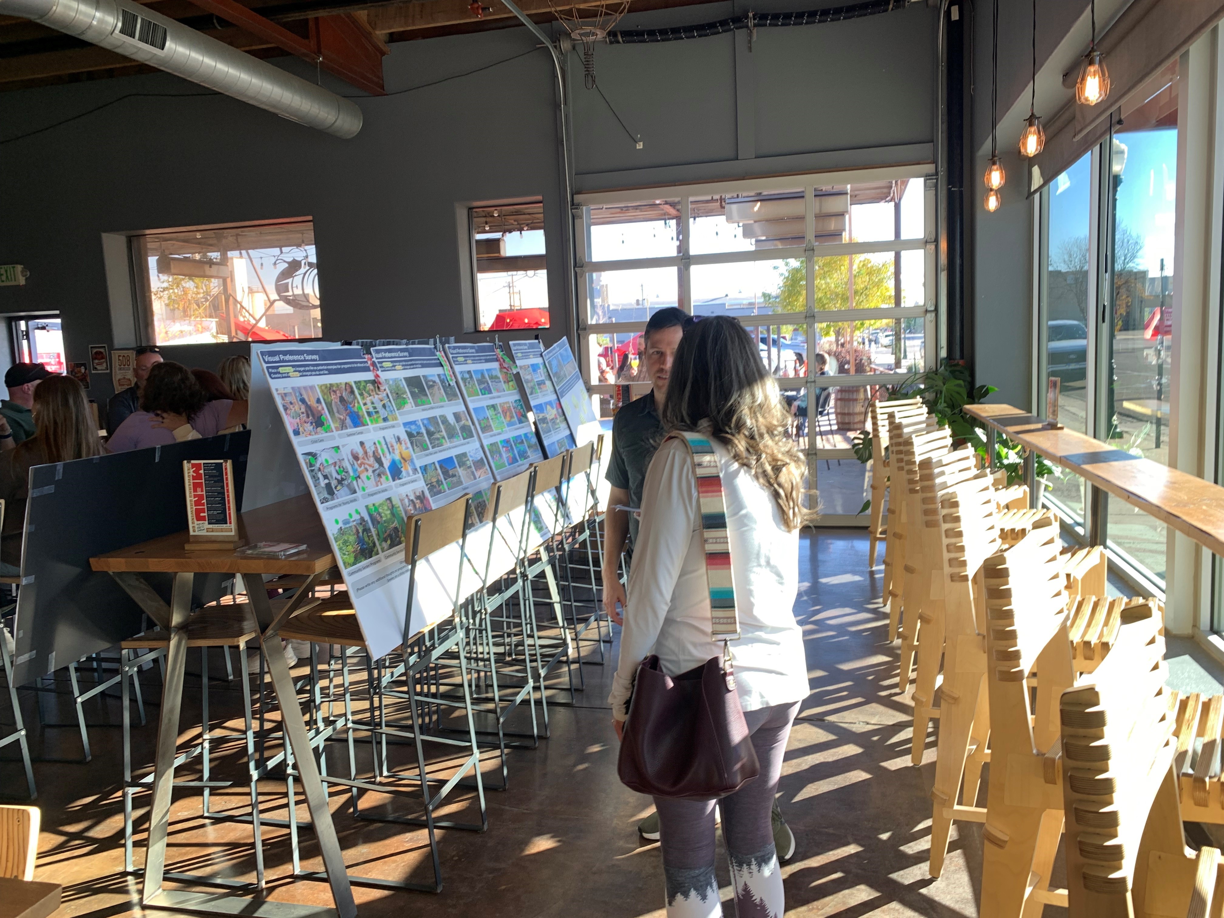 Two people talk in front of a row of display boards inside WeldWerks Brewery.