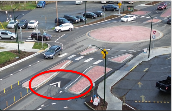 An image showing a new raised speed cushion example on SR 20 approaching a roundabout intersection with Kearney St. in Port Townsend, WA. The speed cushion is approximately 30 feet before the crosswalk.