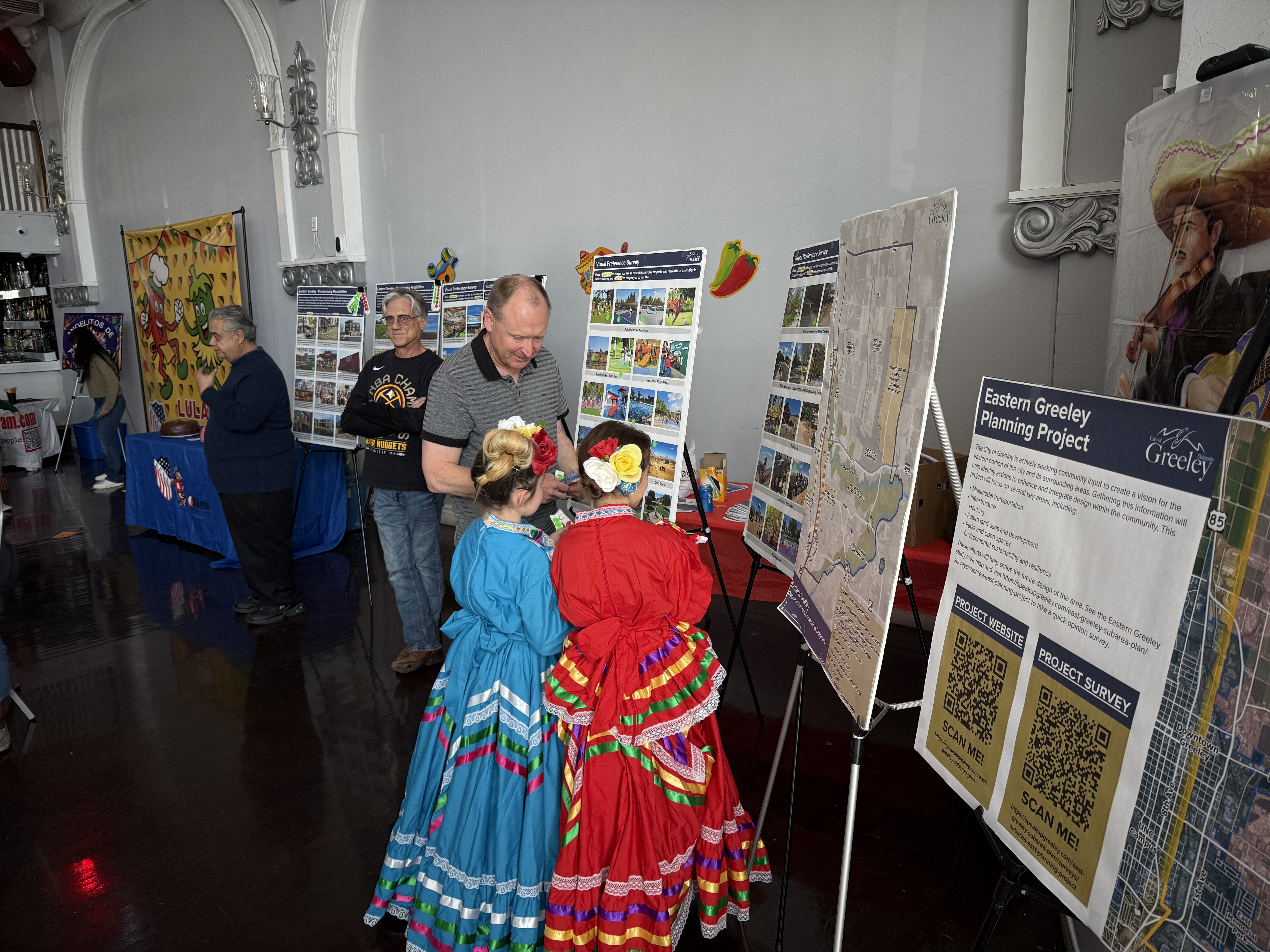 Two children wearing Mexican dresses look at display boards along a wall.