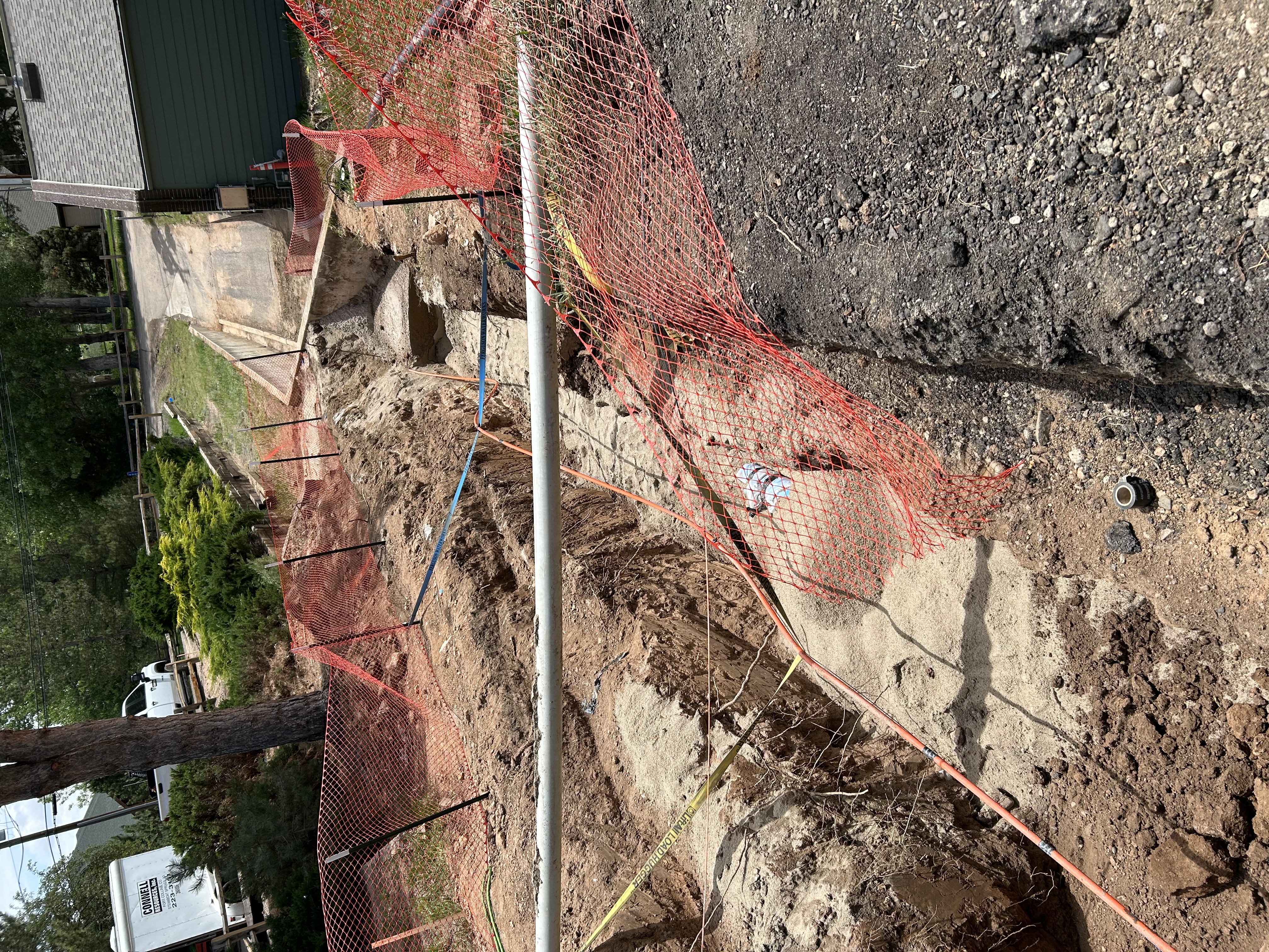 Construction trench with temporary orange fencing around it.