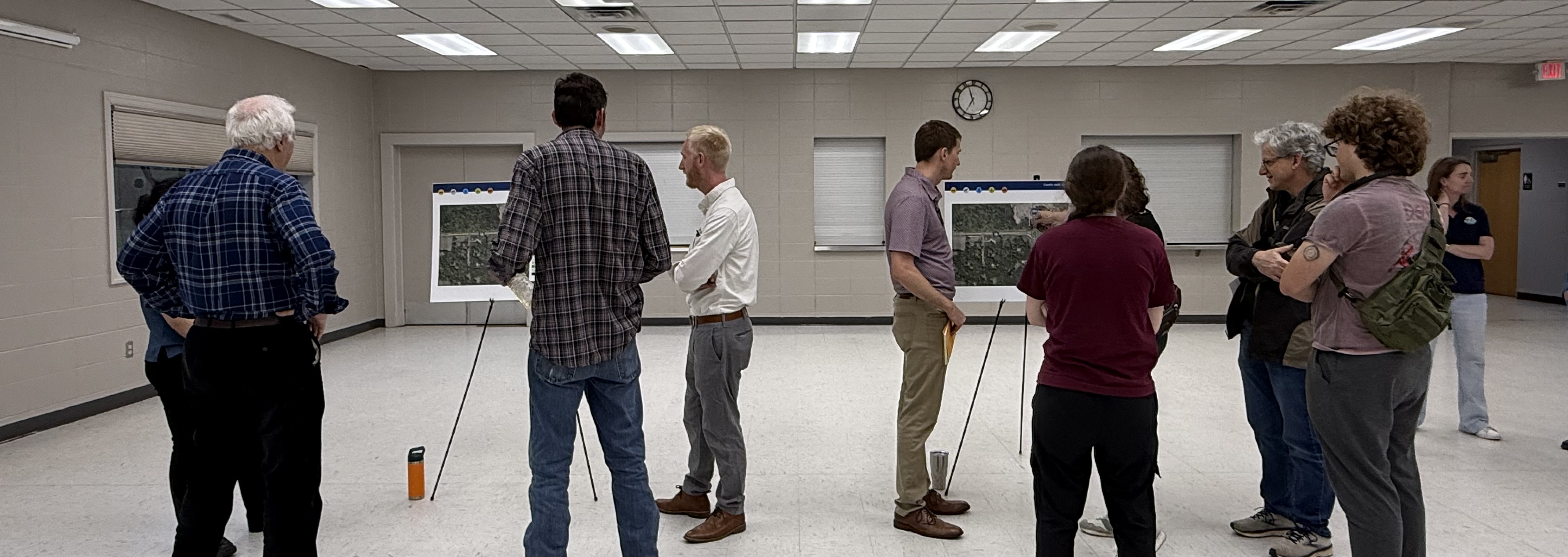 People standing in a room talking and looking at display boards.