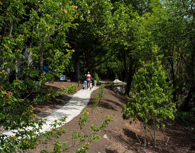 A family walks down a pathway through a wooded area. 