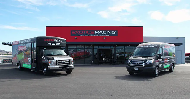 Two branded vans are parked in front of a sleek building with a red Exotics Racing sign. The scene conveys a professional and dynamic tone.