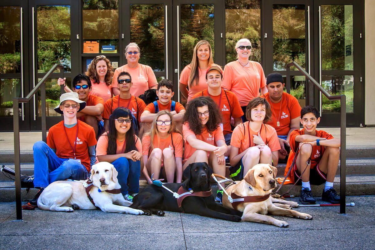 A group shot of camp GDB participants, including three guide dogs. A group shot of camp GDB participants, including three guide dogs.
