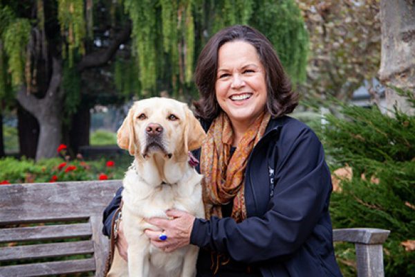 A portrait of Robin Keating with a yellow Lab.