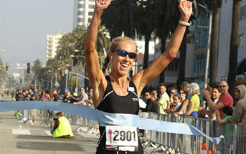 Accomplishments - Santa Monica Laura crossing the finish line at the Santa Monica 10k Classic.