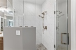 Glass enclosed tiled shower.